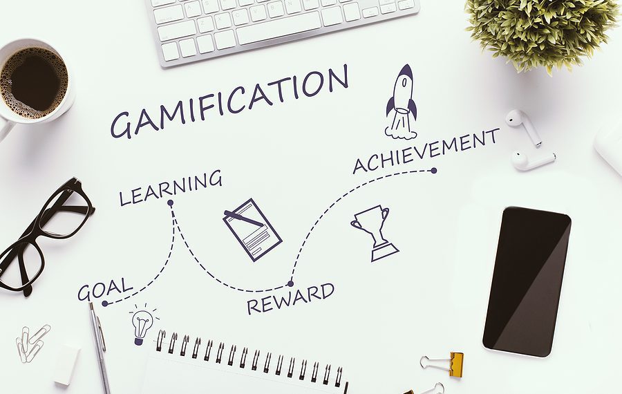 Gamification stages on white workplace - goal, learning, reward and achievement, top view