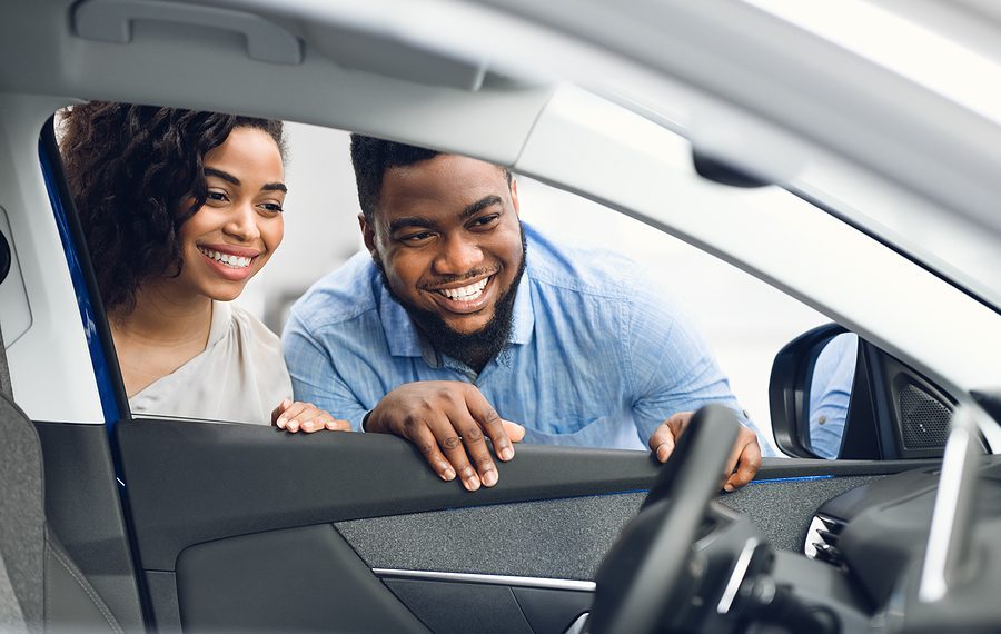 Choosing New Car. African American Spouses Looking At Automobile Interior Buying Vehicle In Dealership Store. Selective Focus